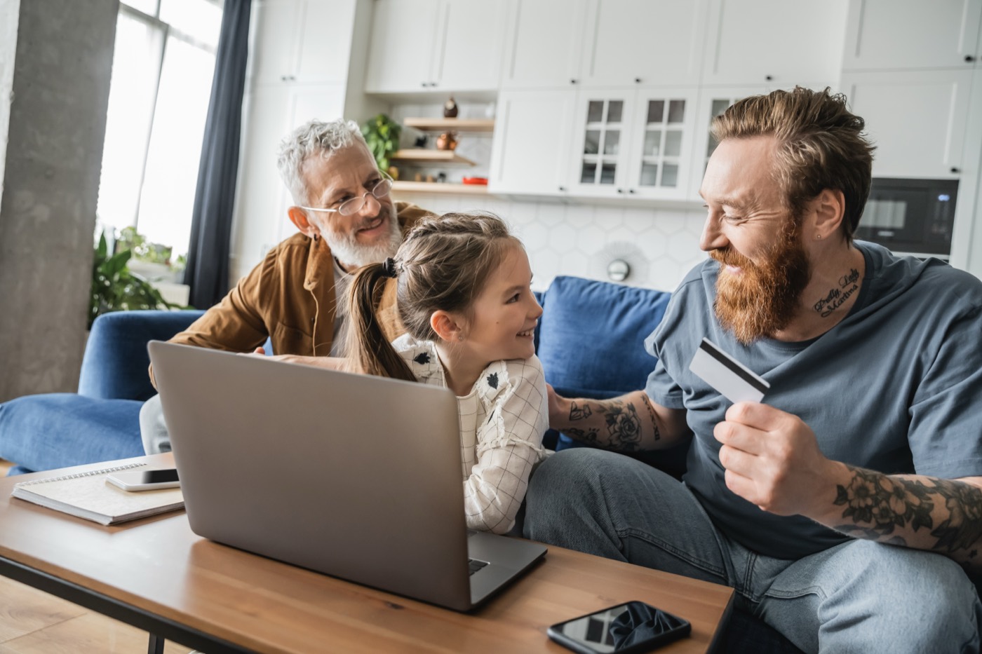 Two parents and their daughter shopping online together with a card