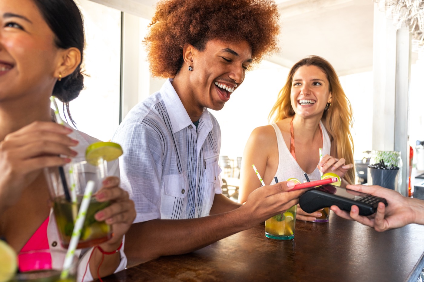 Friends paying with a phone at a bar